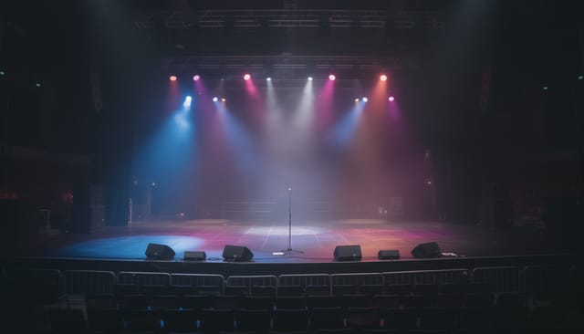 Illustration: Empty concert stage with dramatic coloured spotlights and haze over a microphone stand